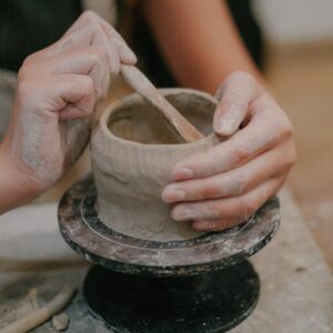 Close-up of a woman shaping a clay pot on a pottery wheel, showcasing craftsmanship.
