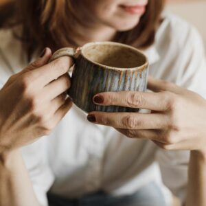Enjoy a relaxing moment with a warm cup of coffee in a handmade mug, perfect for cozy mornings.